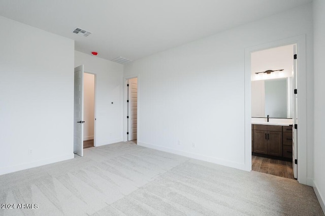 unfurnished bedroom featuring connected bathroom and light colored carpet