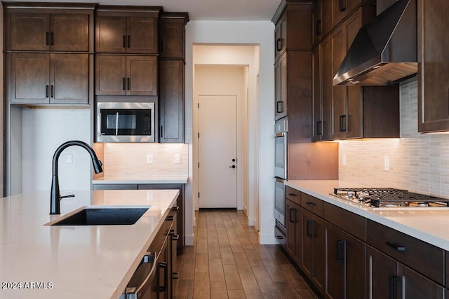 kitchen featuring dark brown cabinets, exhaust hood, stainless steel appliances, sink, and dark hardwood / wood-style floors