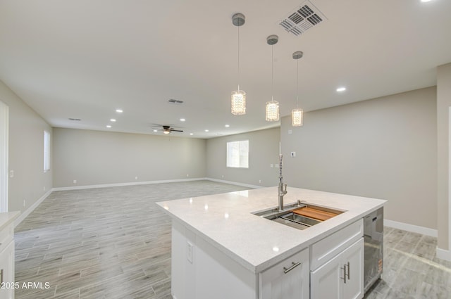 5945 W Lamar Rd, Glendale, AZ 85301 - kitchen with a sink, baseboards, white cabinets, light wood-style flooring, and hanging light fixtures