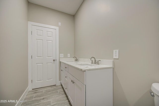 5945 W Lamar Rd, Glendale, AZ 85301 - bathroom featuring double vanity, baseboards, wood finished floors, and toilet