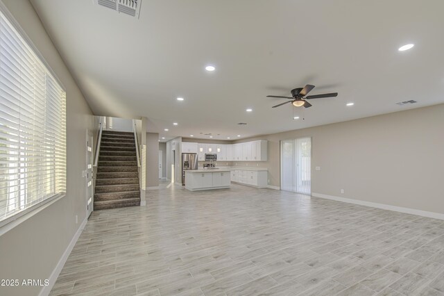5945 W Lamar Rd, Glendale, AZ 85301 - unfurnished living room featuring ceiling fan, recessed lighting, baseboards, stairway, and light wood-style floors