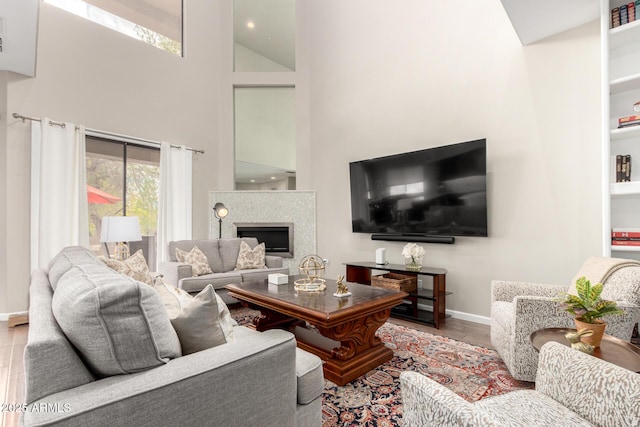 living area with baseboards, a high ceiling, wood finished floors, and a fireplace