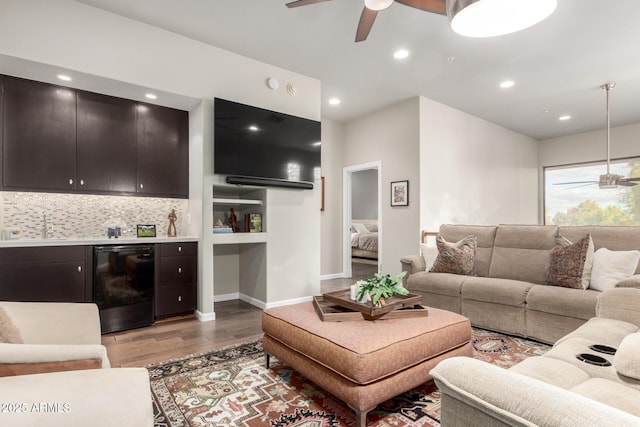 living area featuring beverage cooler, light wood-style flooring, a ceiling fan, recessed lighting, and a bar