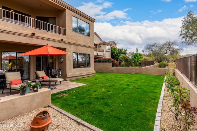 view of yard featuring a patio, a balcony, and a fenced backyard