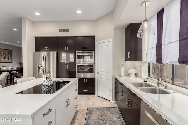 kitchen featuring visible vents, a sink, stainless steel appliances, light countertops, and decorative light fixtures