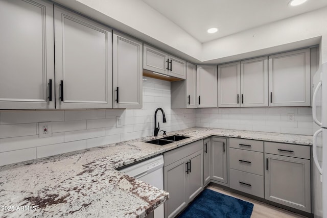 kitchen featuring light stone counters, gray cabinets, and sink