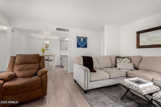 living room featuring a notable chandelier and light wood-type flooring