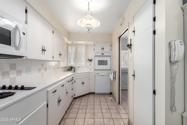 kitchen with tasteful backsplash, white appliances, hanging light fixtures, and white cabinets