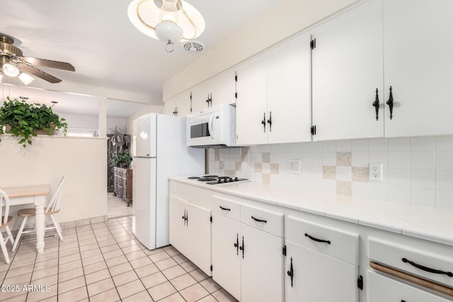 kitchen featuring light tile patterned floors, ceiling fan, white cabinets, white appliances, and backsplash