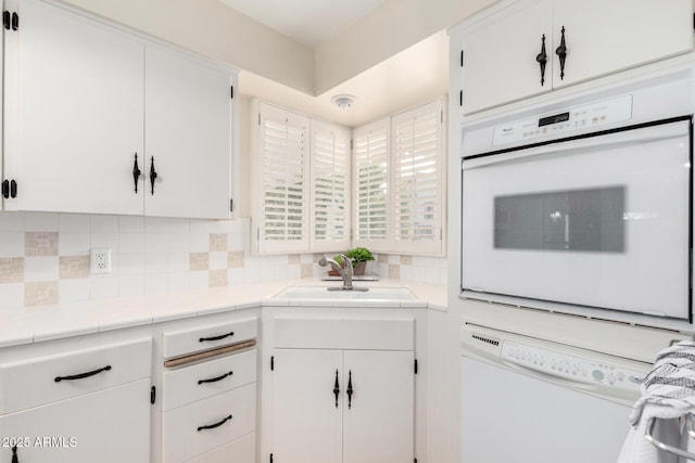 kitchen featuring sink, tile countertops, white cabinets, and white appliances