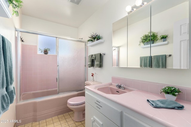 full bathroom featuring vanity, bath / shower combo with glass door, and toilet