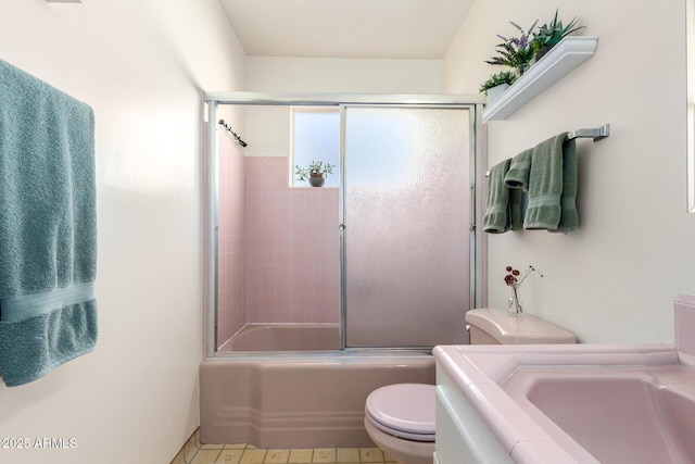 full bathroom with enclosed tub / shower combo, vanity, and toilet