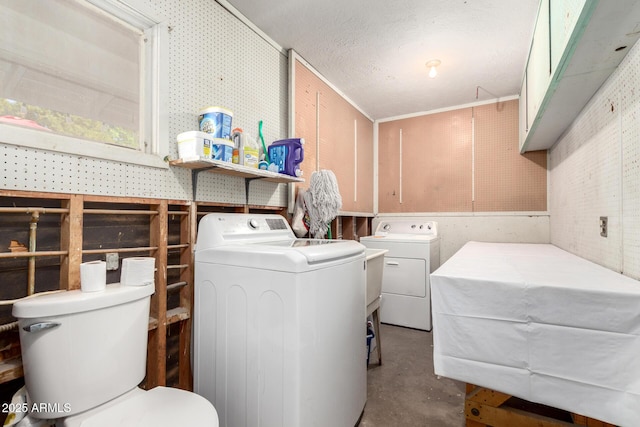 laundry room featuring separate washer and dryer, a workshop area, and a textured ceiling