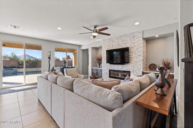 tiled living room with ceiling fan and a fireplace