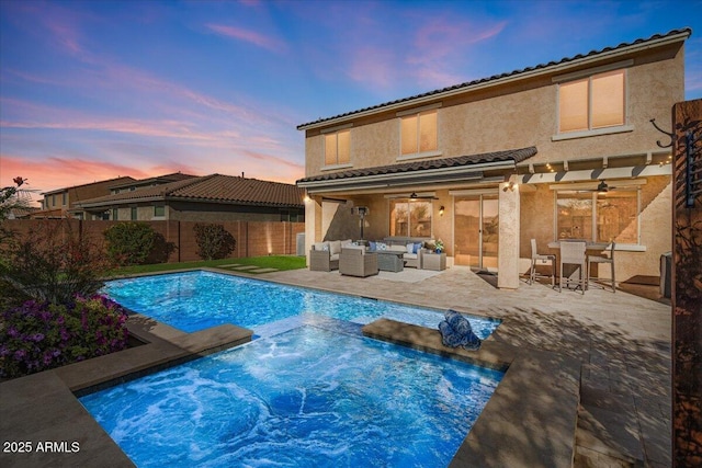 pool at dusk featuring an outdoor living space, a patio, and ceiling fan