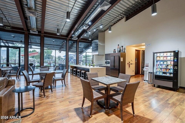 dining area featuring expansive windows, a towering ceiling, and light hardwood / wood-style floors