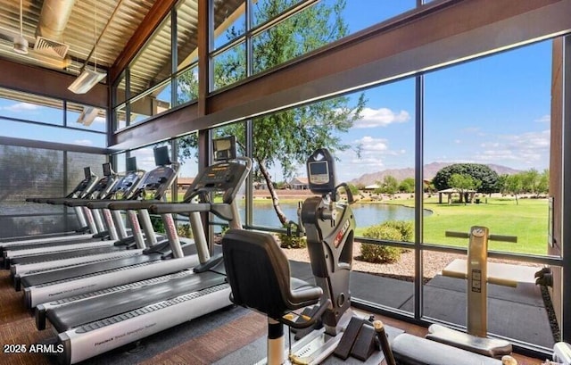 exercise room featuring a water view and a high ceiling