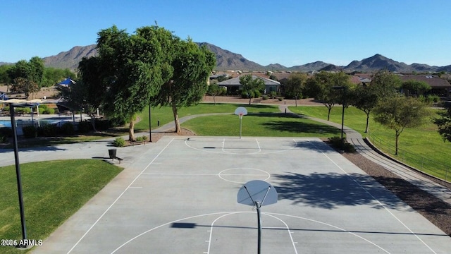 view of sport court with a mountain view and a yard