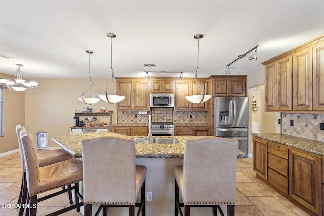 12748 N 57th Dr, Glendale, AZ 85304 - kitchen with appliances with stainless steel finishes, backsplash, an island with sink, a chandelier, and hanging light fixtures
