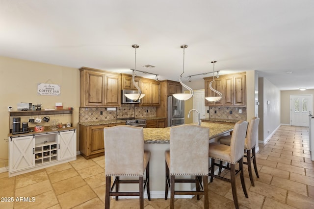 12748 N 57th Dr, Glendale, AZ 85304 - kitchen featuring a breakfast bar, backsplash, stainless steel appliances, baseboards, and a kitchen island with sink