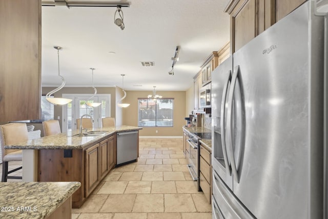 12748 N 57th Dr, Glendale, AZ 85304 - kitchen featuring stainless steel appliances, a sink, track lighting, brown cabinets, and a breakfast bar area