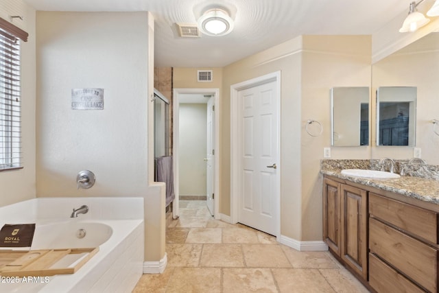 12748 N 57th Dr, Glendale, AZ 85304 - full bathroom with stone tile flooring, a garden tub, vanity, a shower stall, and plenty of natural light