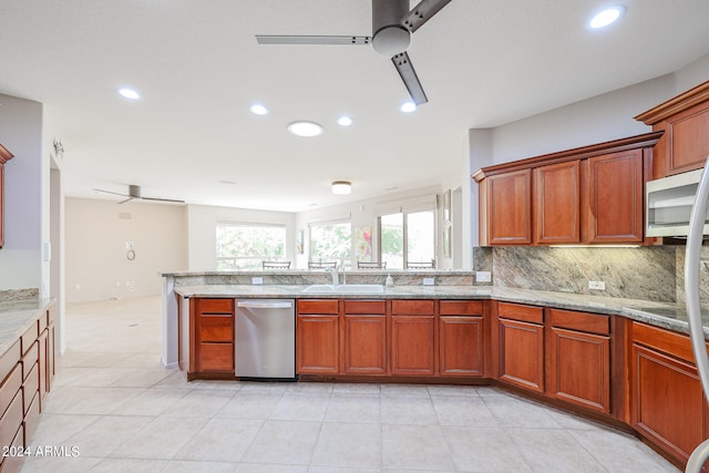 kitchen featuring light stone countertops, backsplash, appliances with stainless steel finishes, ceiling fan, and sink