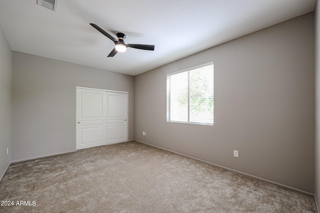 unfurnished bedroom with light colored carpet, ceiling fan, and a closet