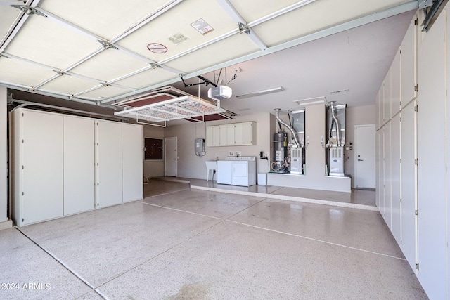 garage with water heater, a garage door opener, and washer and dryer