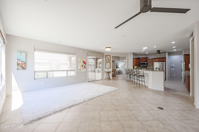 kitchen featuring stainless steel appliances, a kitchen bar, plenty of natural light, and light tile patterned floors