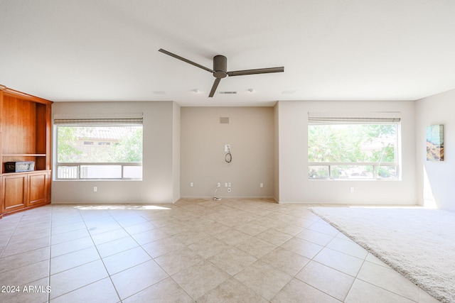 tiled empty room with ceiling fan and plenty of natural light