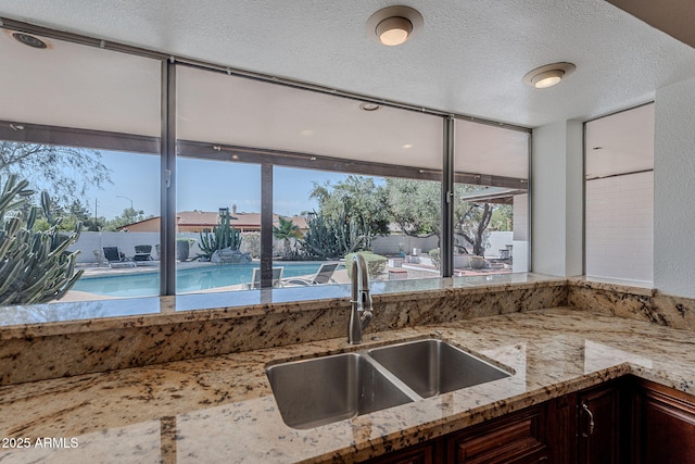 5539 E Dahlia Dr, Scottsdale, AZ 85254 - kitchen with a sink, light stone counters, dark brown cabinetry, and a textured ceiling