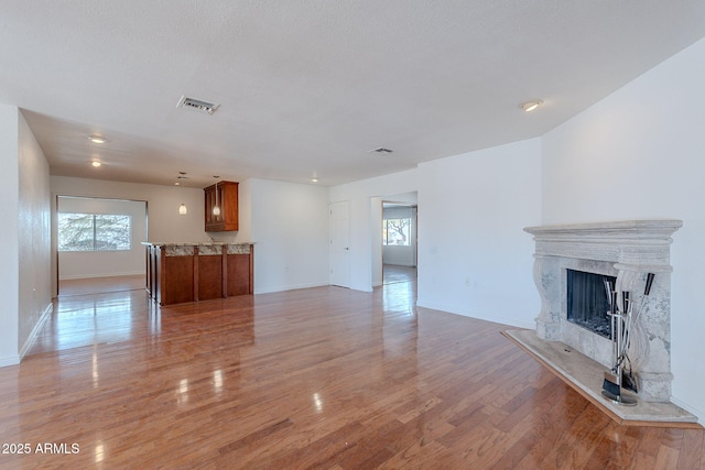 5539 E Dahlia Dr, Scottsdale, AZ 85254 - unfurnished living room with plenty of natural light, light wood-style flooring, baseboards, and a high end fireplace