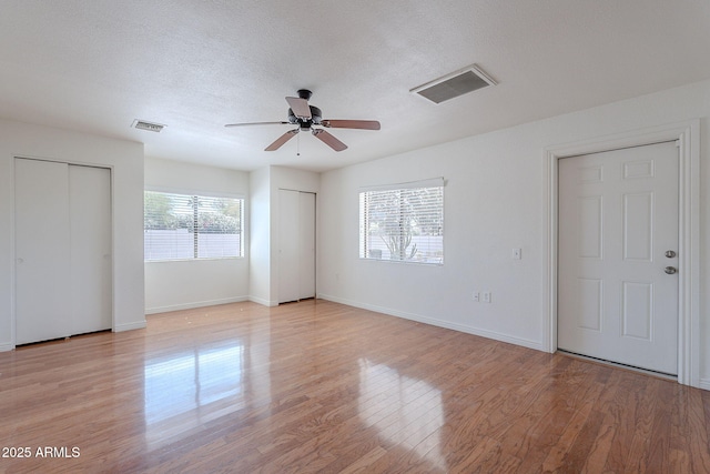 5539 E Dahlia Dr, Scottsdale, AZ 85254 - unfurnished bedroom with multiple closets, light wood-style flooring, baseboards, ceiling fan, and a textured ceiling