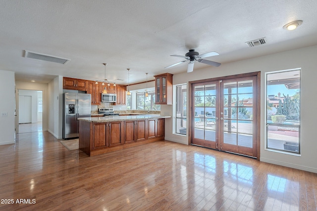5539 E Dahlia Dr, Scottsdale, AZ 85254 - kitchen featuring stainless steel appliances, brown cabinetry, light wood-style floors, a peninsula, and baseboards