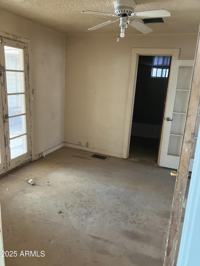 unfurnished room with ceiling fan and a textured ceiling