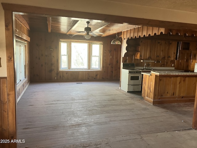 kitchen with stainless steel range with electric stovetop, wood ceiling, wooden walls, ceiling fan, and beamed ceiling