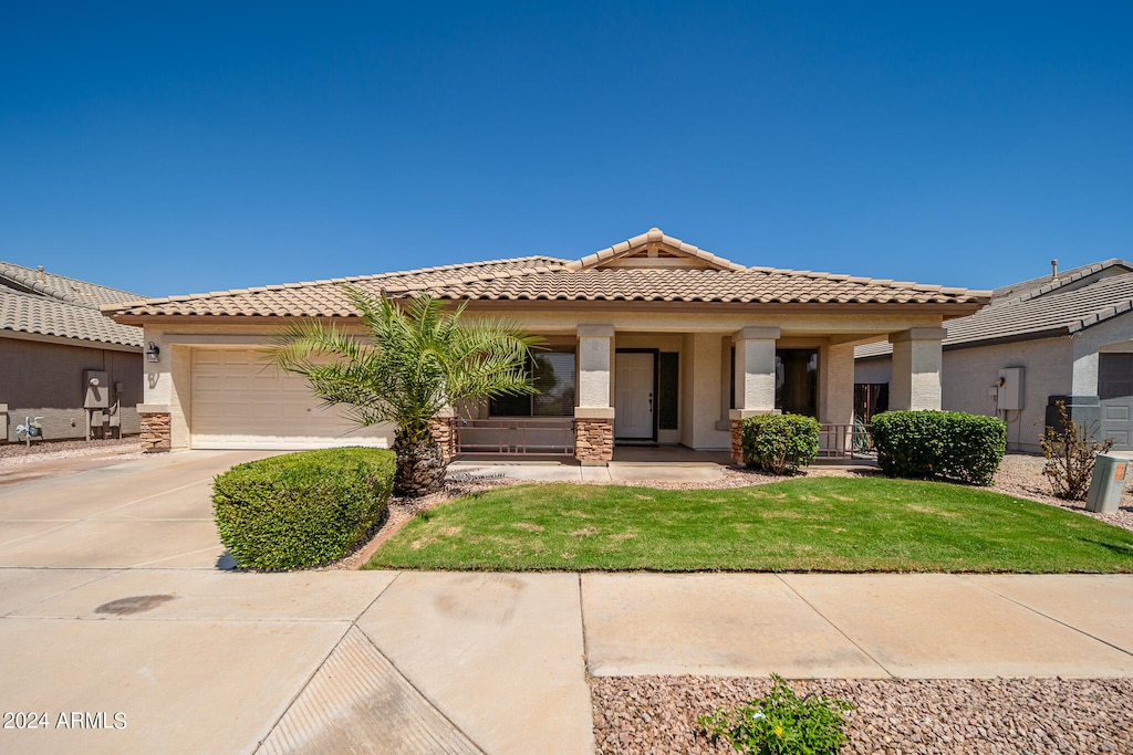 mediterranean / spanish home featuring a garage and a front lawn