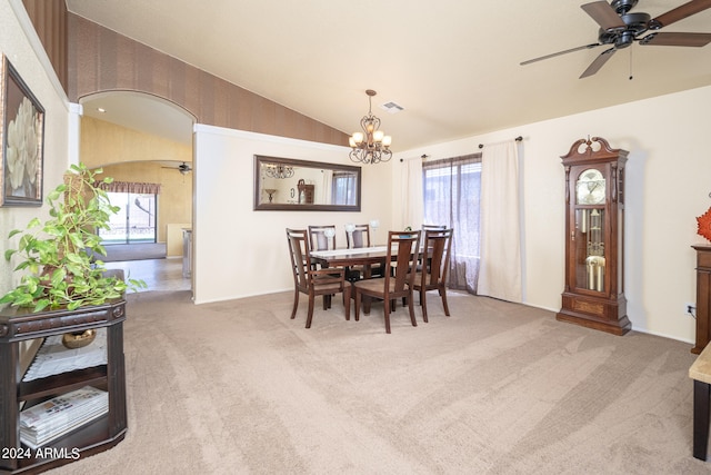 dining space with a wealth of natural light, vaulted ceiling, carpet floors, and ceiling fan with notable chandelier