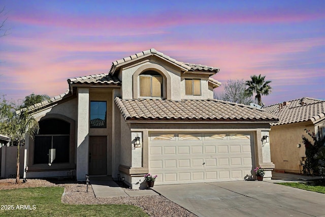 mediterranean / spanish home with a tile roof, driveway, an attached garage, and stucco siding