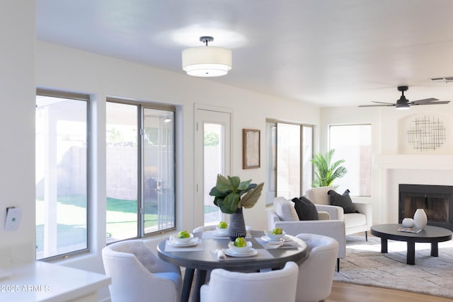 dining area with light wood finished floors, visible vents, and a tiled fireplace