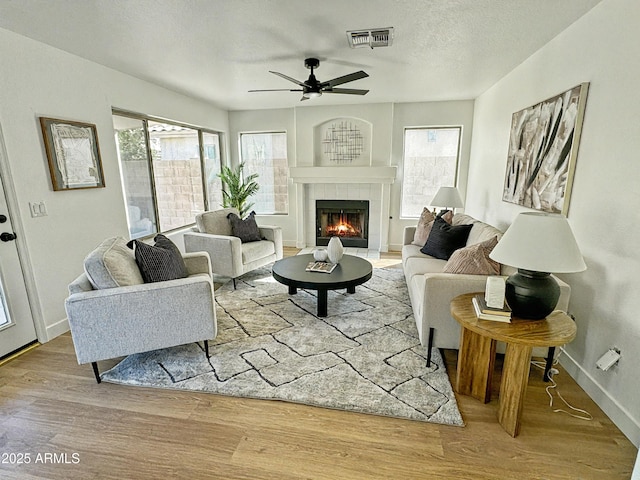 living room with a textured ceiling, a healthy amount of sunlight, a fireplace, and light wood-style floors