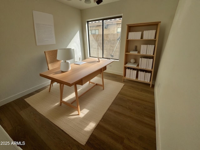 home office with dark wood finished floors, a ceiling fan, and baseboards