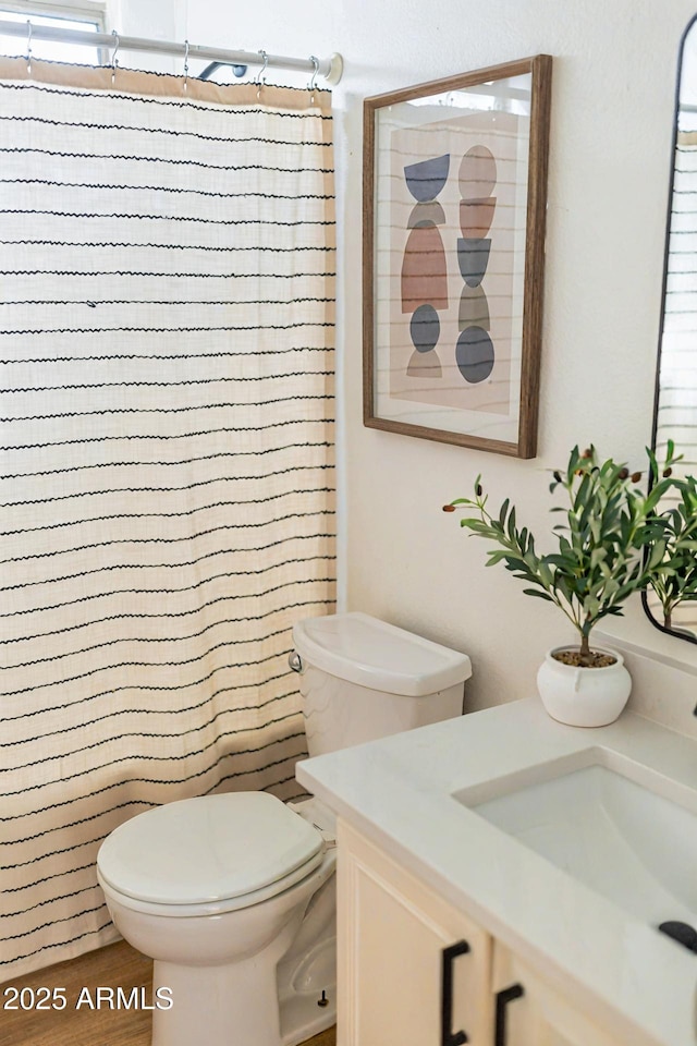 bathroom with curtained shower, vanity, and toilet