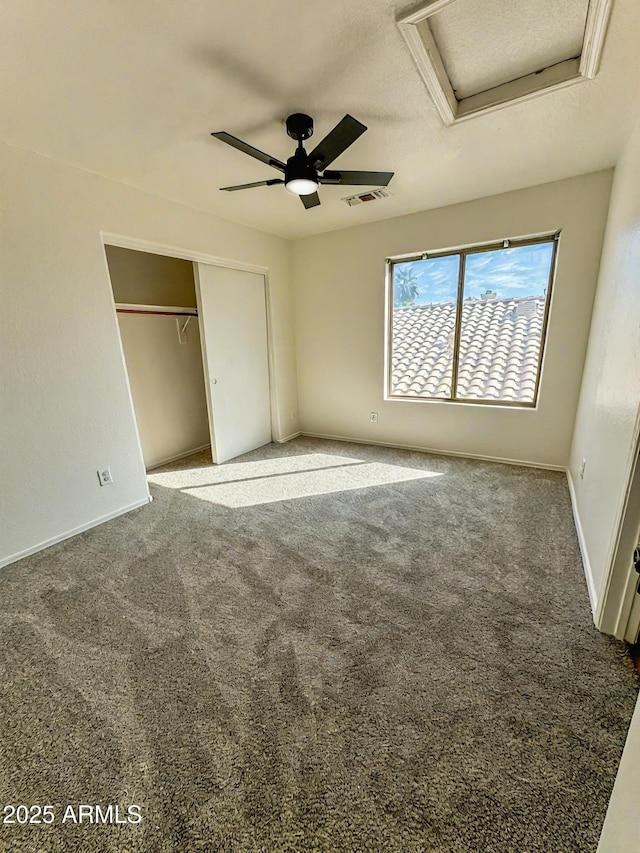 unfurnished bedroom featuring visible vents, baseboards, a closet, carpet, and attic access