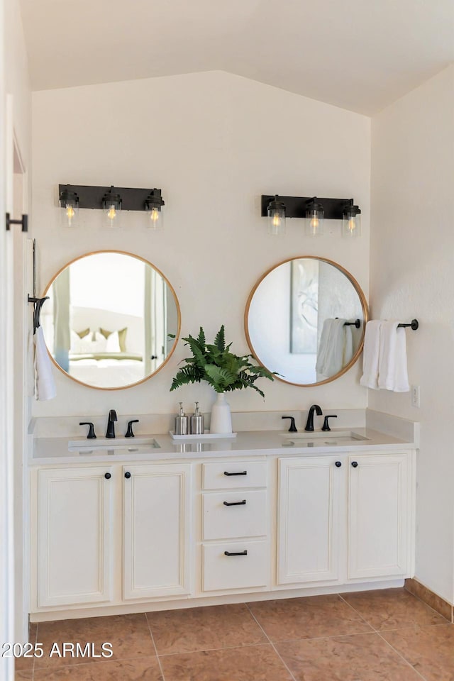 bathroom featuring vaulted ceiling, double vanity, a sink, and tile patterned floors