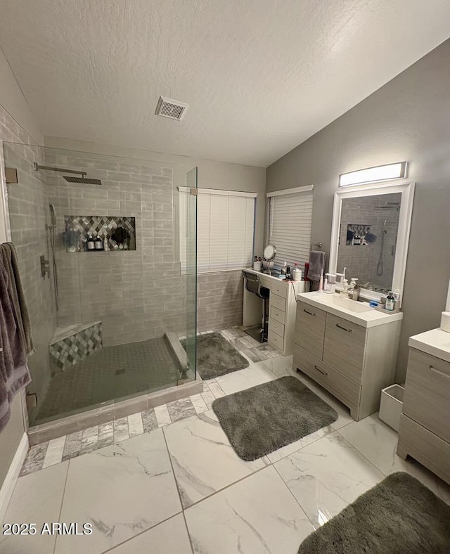 135 S Abalone Dr, Gilbert, AZ 85233 - bathroom featuring marble look tile flooring, a stall shower, vanity, vaulted ceiling, and a textured ceiling