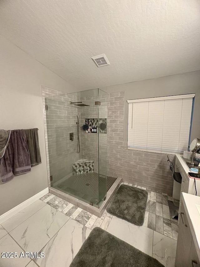 135 S Abalone Dr, Gilbert, AZ 85233 - bathroom featuring marble look tile flooring, a shower stall, baseboards, a textured ceiling, and vanity