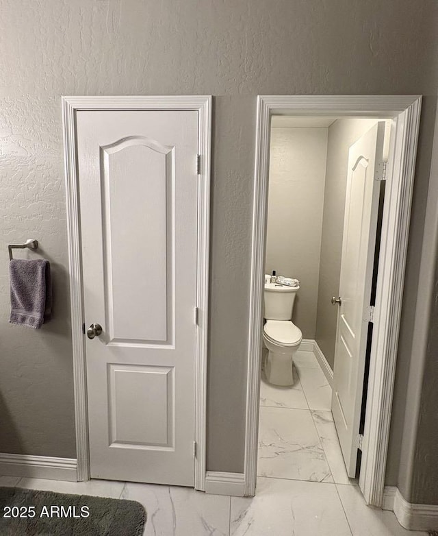 135 S Abalone Dr, Gilbert, AZ 85233 - bathroom featuring marble look tiles, baseboards, toilet, and a textured wall
