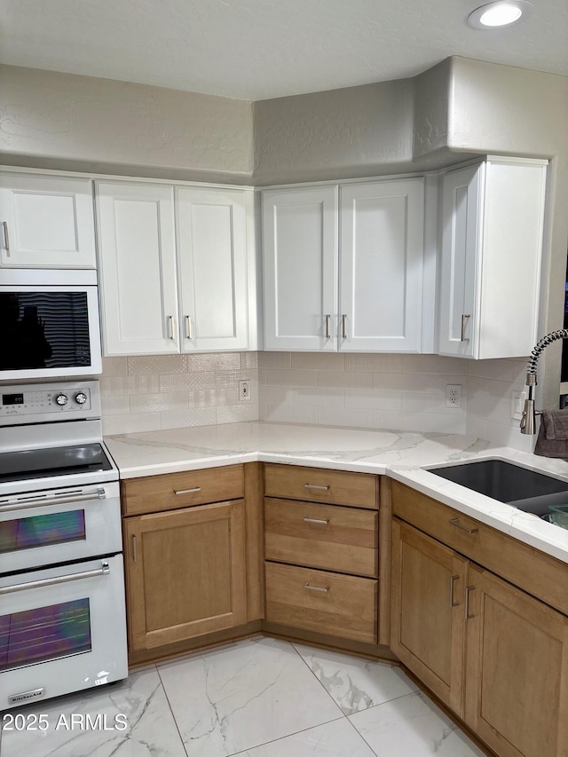 135 S Abalone Dr, Gilbert, AZ 85233 - kitchen with range with two ovens, a sink, light marble finish floors, white cabinetry, and decorative backsplash